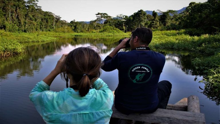 Travelers taking photos on a balsa raft at Machu Wasi lake